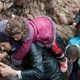 A migrant woman carries her child after arriving at a rocky beach on the Greek island of Lesbos.